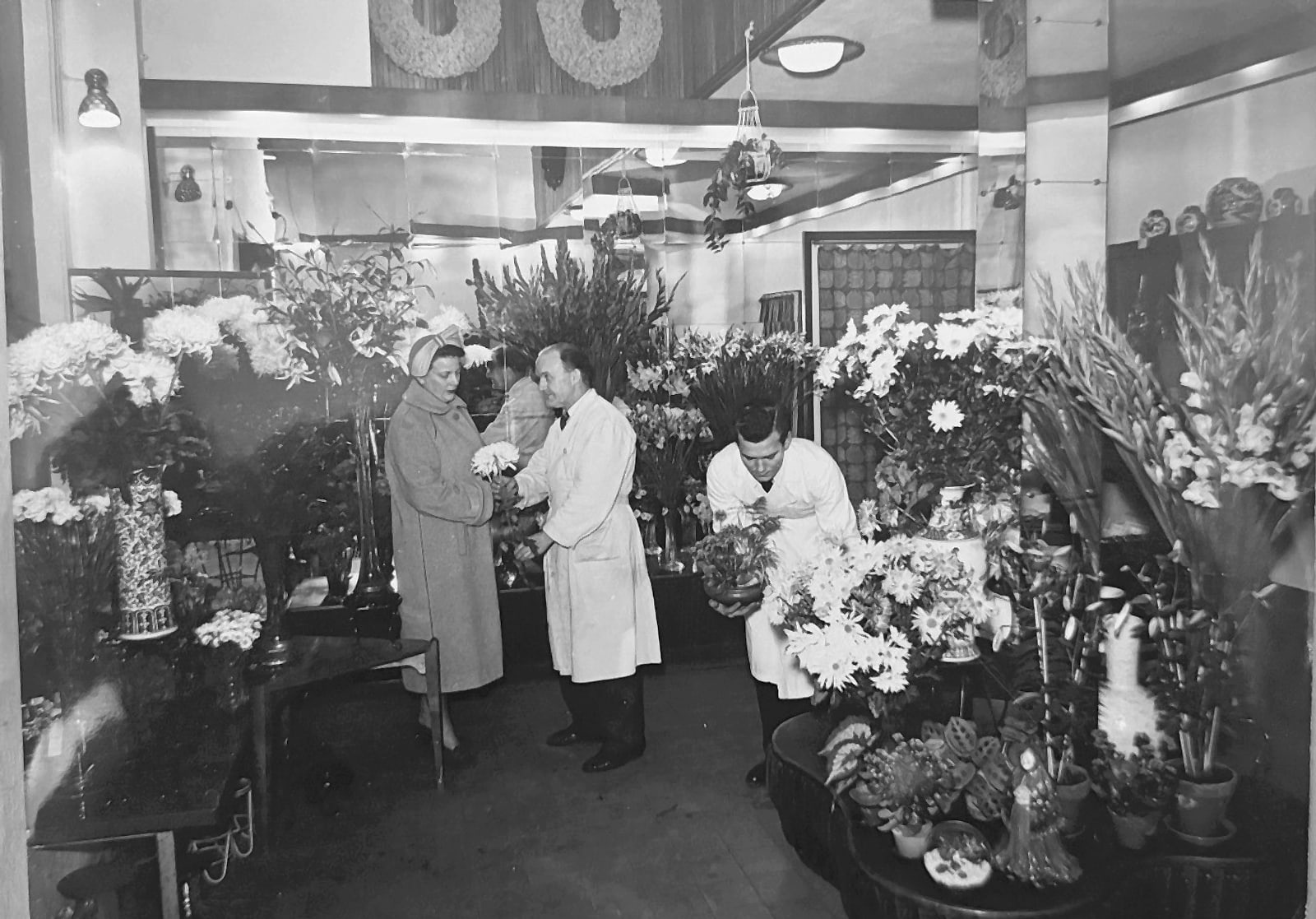 Interiör från Melanders butik med två floristerna i vita rockar och en kund