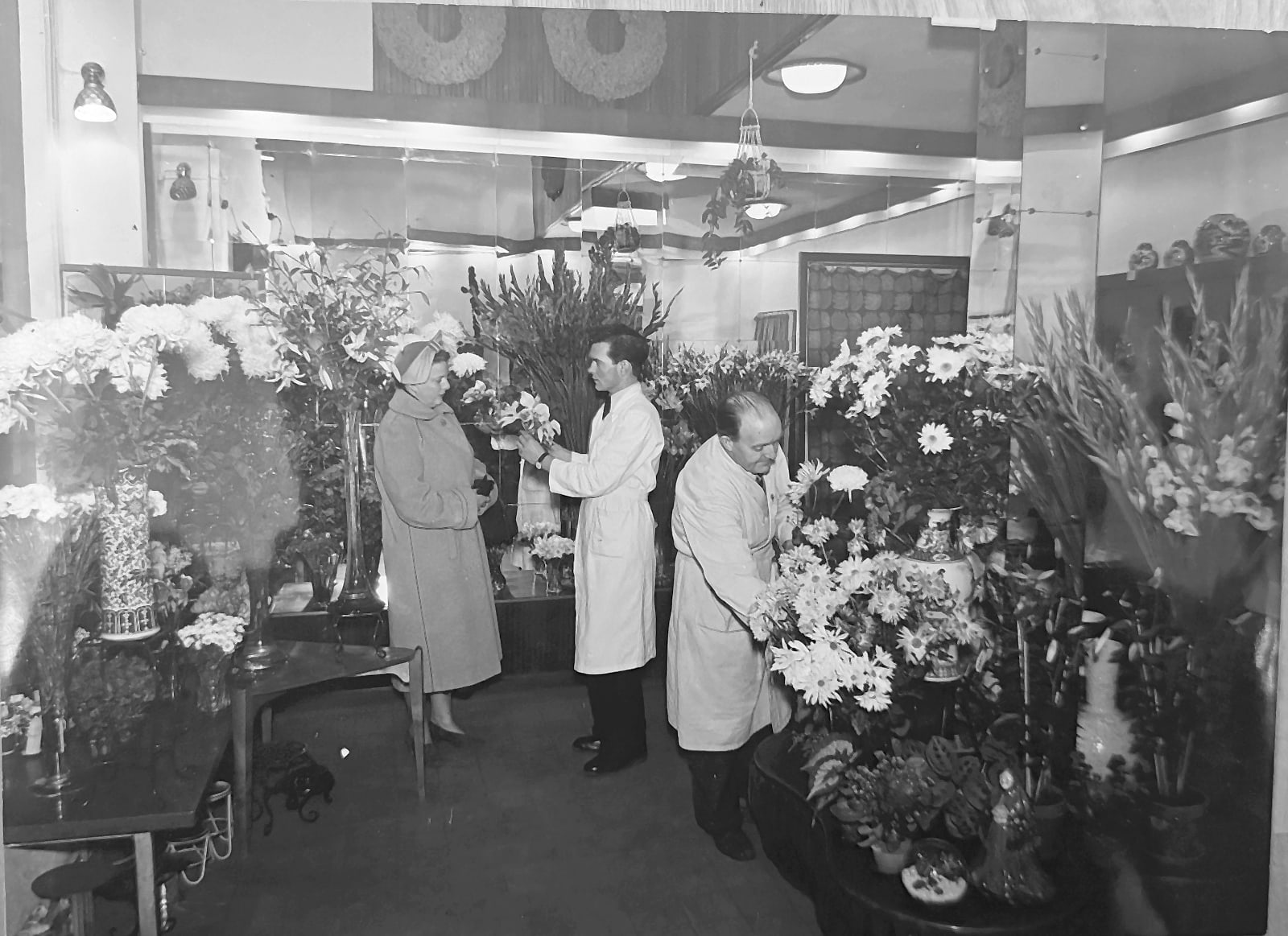 Interiör från Melanders butik med två floristerna i vita rockar och en kund